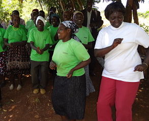 Mercy Karunditu, GBM Senior Project Officer, dances with Kimara G3 Self-help Group in Kangema.